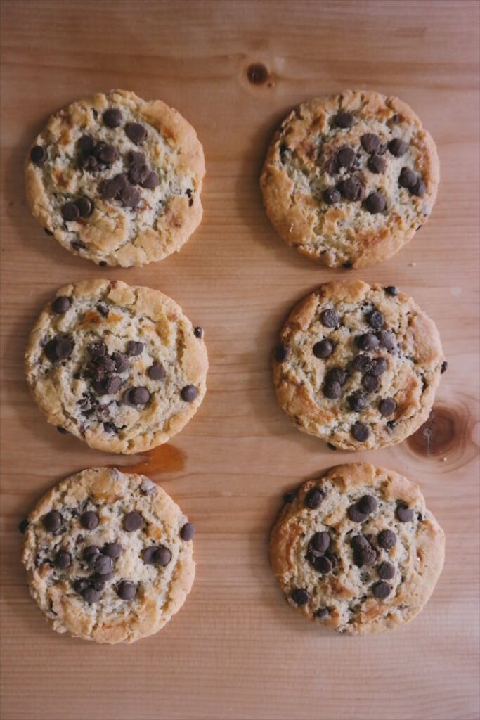 Freshly baked chocolate chip cookies arranged on a wooden surface, showcasing their tasty appeal.